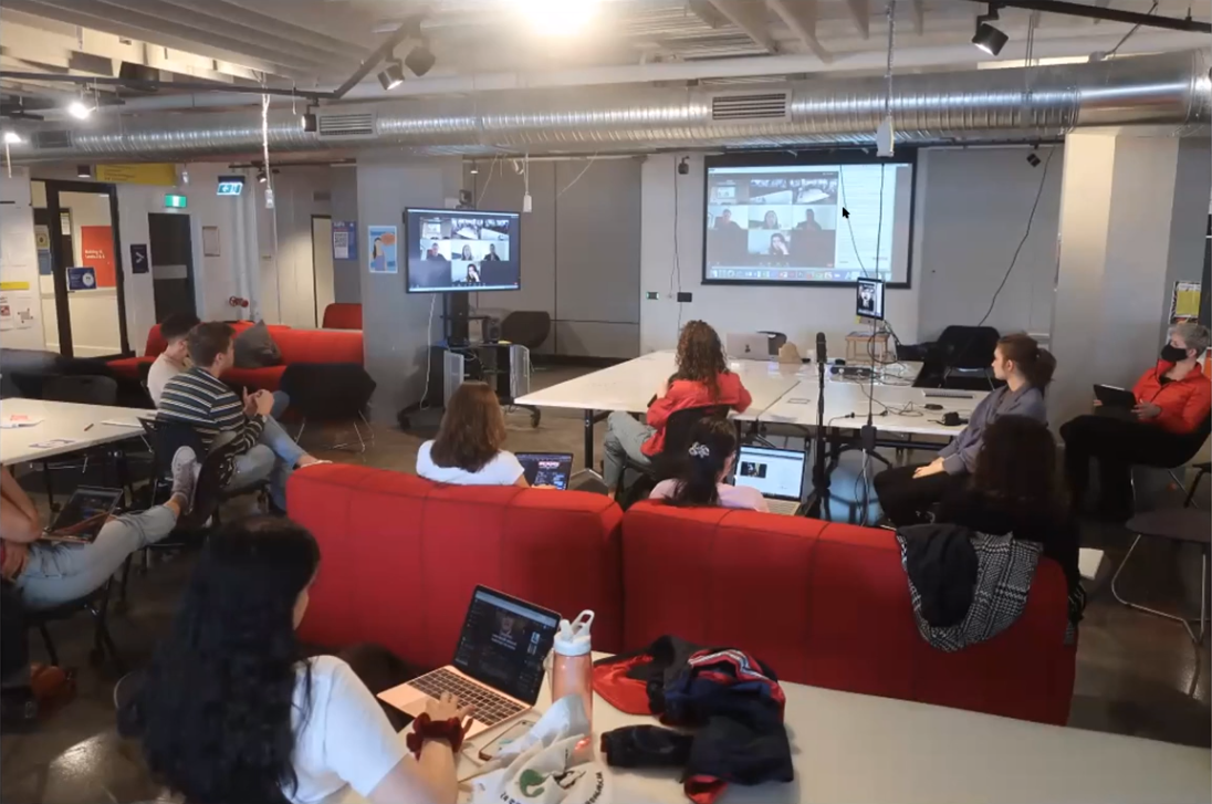 Students sitting in the classroom and collectively talking to other students on Zoom during Bert's mixed mode class.